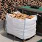 Ferring Firewood bulk bag loaded on a pallet, ready for delivery, with stacked seasoned logs in the yard behind.