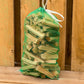 Here is a photo of our dry bags of kindling white pairs perfectly with our seasoned and kiln dried firewood. Green bag against wooden background.