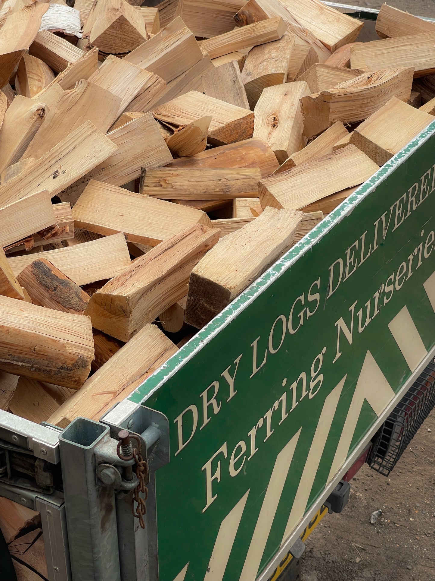 A close-up photograph of our full load of seasoned firewood loaded into the back of our local delivery van.  Showing the back of the tailgate and the high quality of the dry logs.